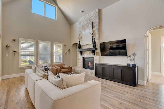 living room featuring a towering ceiling, light hardwood / wood-style floors, and a fireplace