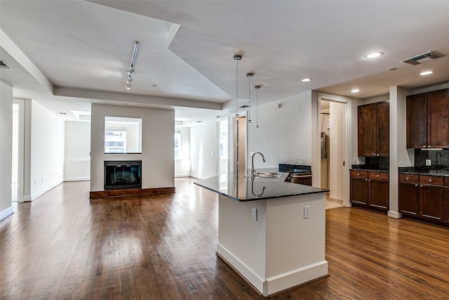 kitchen with pendant lighting, sink, track lighting, dark brown cabinetry, and dark hardwood / wood-style flooring