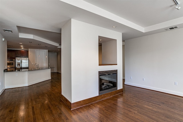 unfurnished living room with sink and dark wood-type flooring