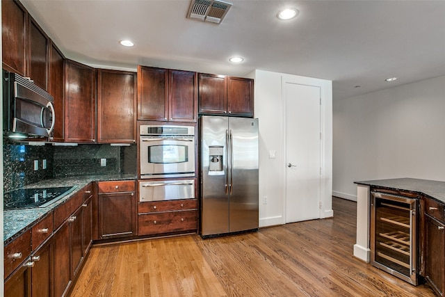 kitchen featuring wine cooler, stainless steel appliances, tasteful backsplash, and light wood-type flooring