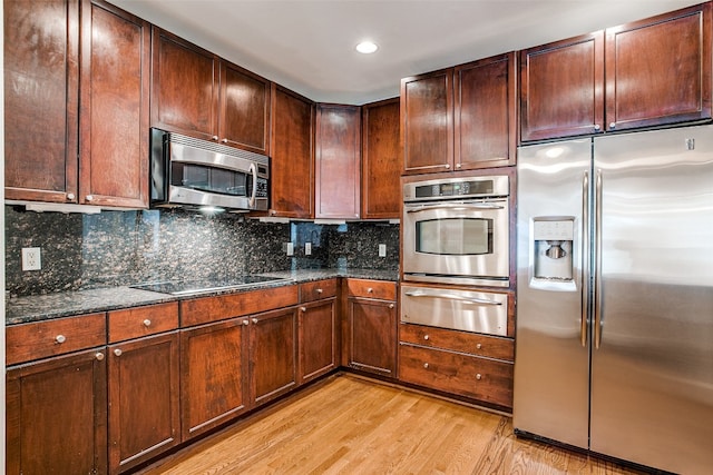 kitchen with light hardwood / wood-style floors, tasteful backsplash, stainless steel appliances, and dark stone counters