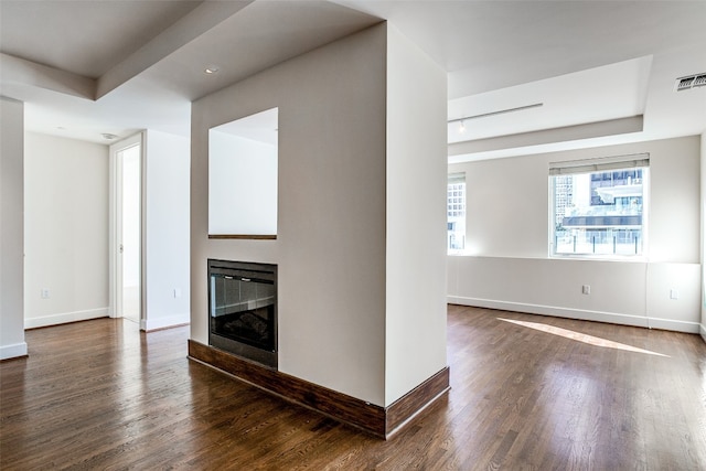 unfurnished living room with dark hardwood / wood-style flooring and a tray ceiling