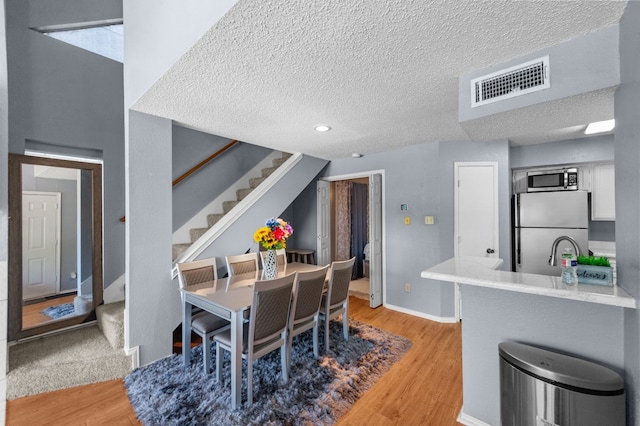 dining area featuring sink, light hardwood / wood-style floors, and a textured ceiling