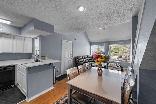 dining room with light hardwood / wood-style flooring, a textured ceiling, and lofted ceiling