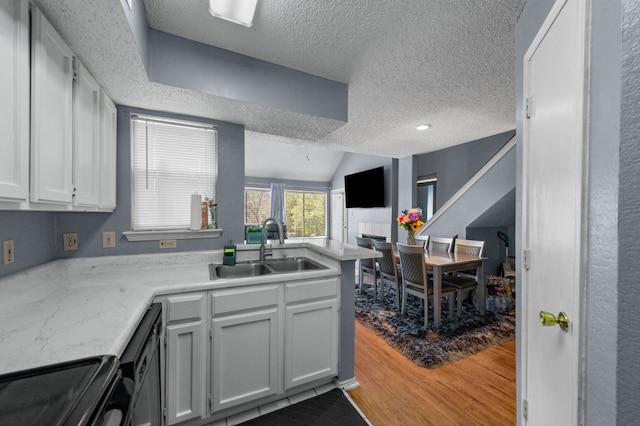 kitchen with wood-type flooring, sink, white cabinets, and stove