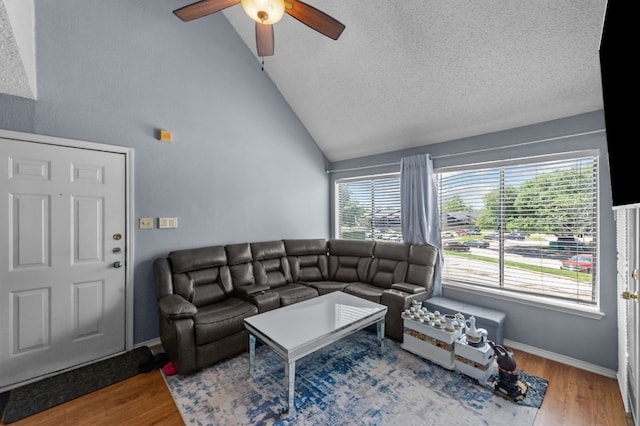 living room featuring high vaulted ceiling, ceiling fan, a textured ceiling, and light wood-type flooring