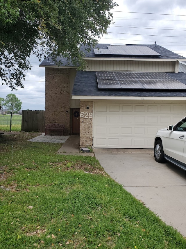 view of front of property featuring a front lawn, a garage, and solar panels