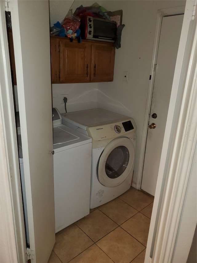 washroom with cabinets, hookup for an electric dryer, light tile flooring, and washing machine and clothes dryer