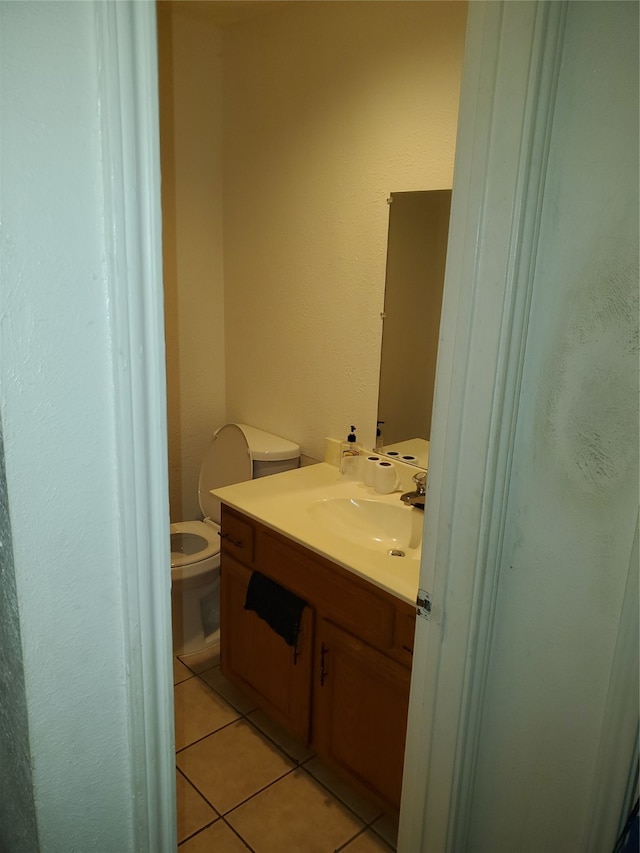 bathroom featuring tile flooring, toilet, and vanity