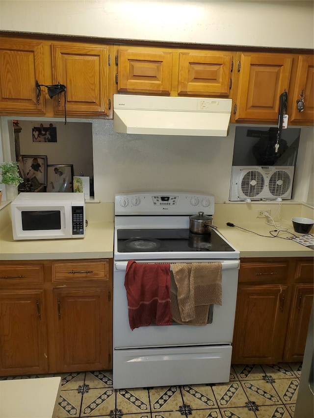 kitchen with ventilation hood, white appliances, and light tile floors