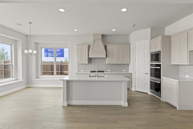 kitchen with sink, decorative backsplash, custom exhaust hood, and light hardwood / wood-style floors