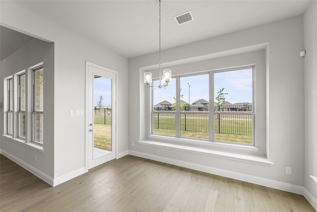 unfurnished dining area featuring light hardwood / wood-style flooring and a notable chandelier