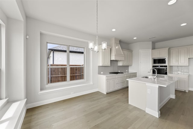 kitchen featuring premium range hood, pendant lighting, built in microwave, sink, and oven