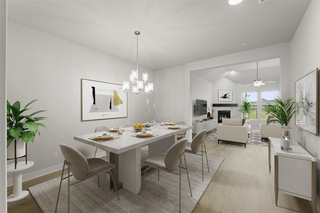 dining area featuring vaulted ceiling, ceiling fan with notable chandelier, and light wood-type flooring