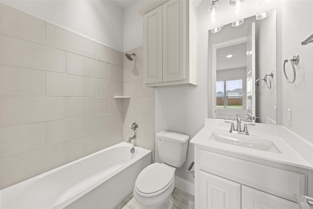 full bathroom featuring vanity, tiled shower / bath, and toilet