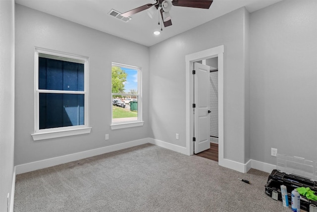 interior space with ceiling fan, ensuite bathroom, and dark colored carpet