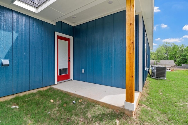 property entrance with a patio area, a yard, and central AC