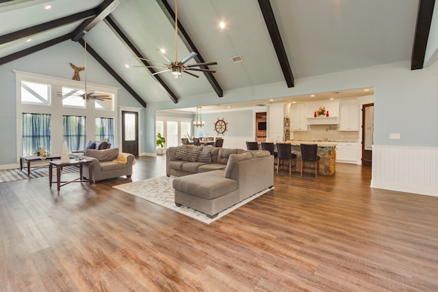 living room featuring light wood-type flooring, beam ceiling, and high vaulted ceiling