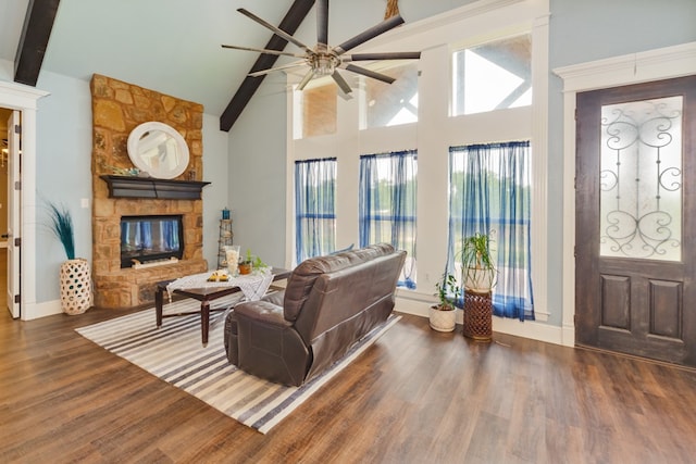 living room with ceiling fan, dark hardwood / wood-style floors, beam ceiling, high vaulted ceiling, and a fireplace