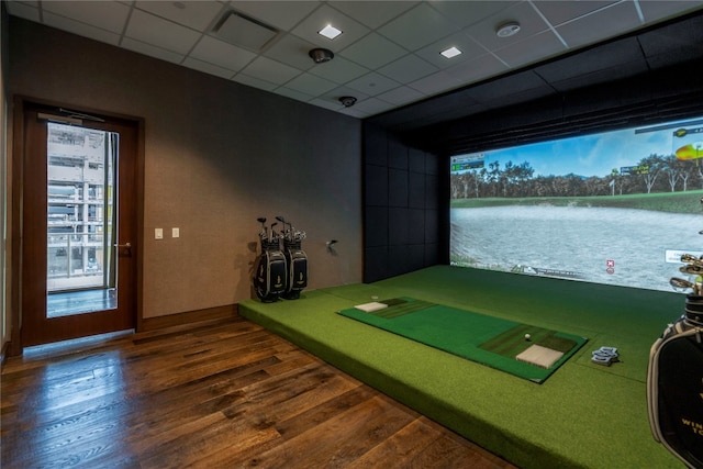 rec room featuring a drop ceiling, golf simulator, dark hardwood / wood-style floors, and a water view