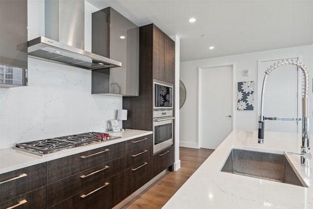 kitchen featuring wall chimney exhaust hood, dark hardwood / wood-style flooring, backsplash, stainless steel appliances, and sink