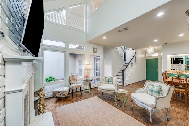 living room with a towering ceiling, a fireplace, and parquet flooring