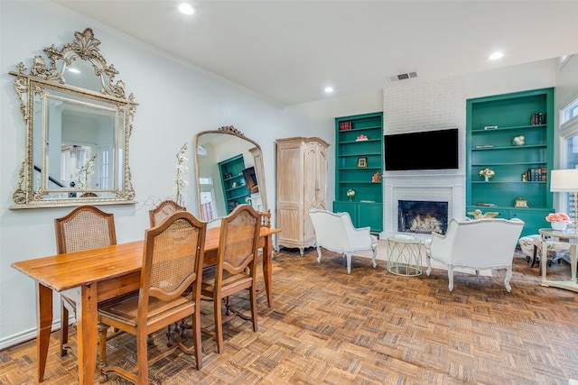 dining room featuring a brick fireplace, ornamental molding, parquet floors, and built in shelves