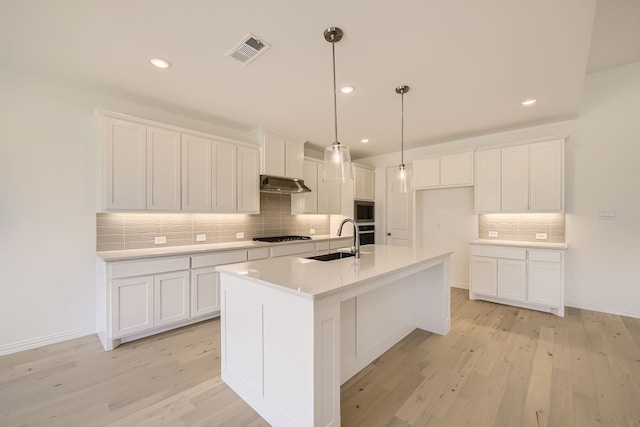 kitchen featuring decorative backsplash, light hardwood / wood-style floors, sink, and white cabinets