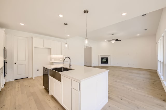 kitchen with a center island with sink, white cabinetry, stainless steel appliances, and light wood-type flooring