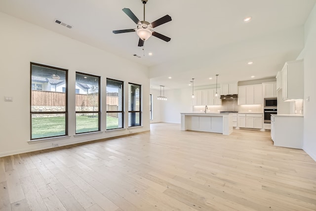 unfurnished living room with light hardwood / wood-style flooring, sink, and ceiling fan