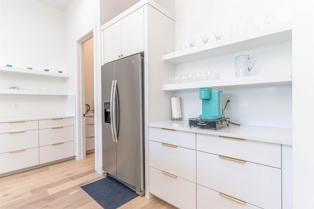 kitchen with light hardwood / wood-style floors, stainless steel fridge, and white cabinetry