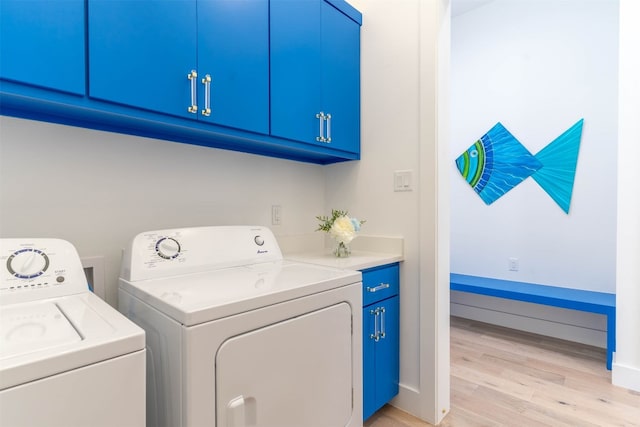 laundry area with cabinets, washing machine and dryer, and light wood-type flooring