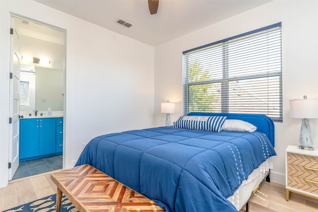 bedroom with sink, ceiling fan, light wood-type flooring, and ensuite bathroom