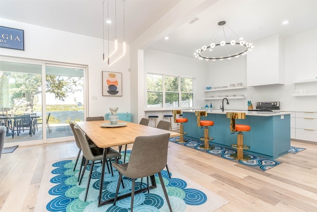 dining area with beamed ceiling, light hardwood / wood-style flooring, and a notable chandelier