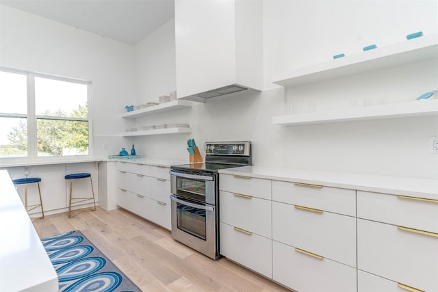 kitchen with double oven range, light hardwood / wood-style flooring, and white cabinetry