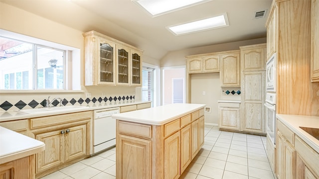 kitchen with light brown cabinetry, tasteful backsplash, white appliances, and a center island