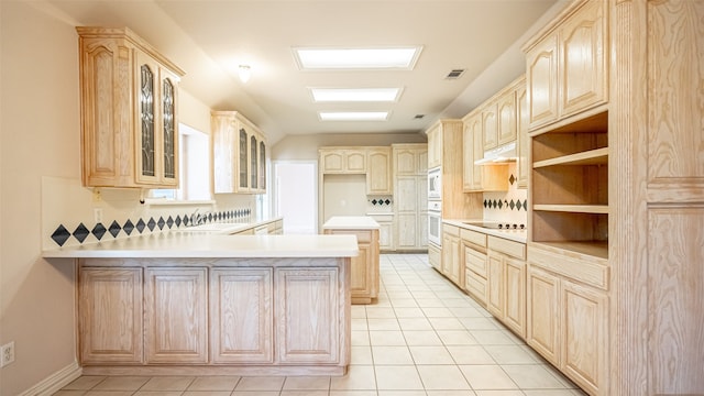 kitchen with white appliances, kitchen peninsula, light brown cabinetry, and tasteful backsplash