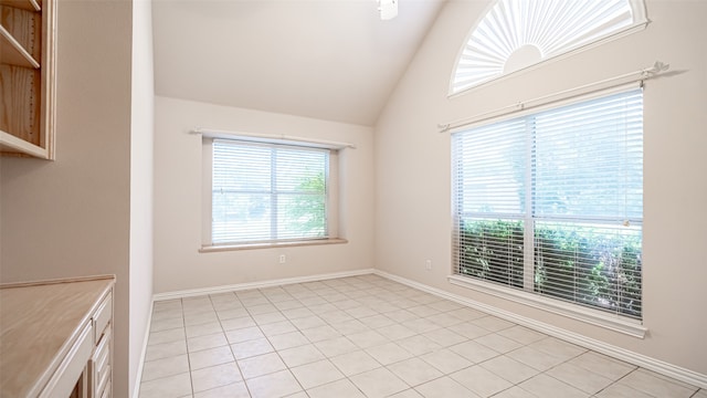 unfurnished room featuring high vaulted ceiling and light tile patterned floors