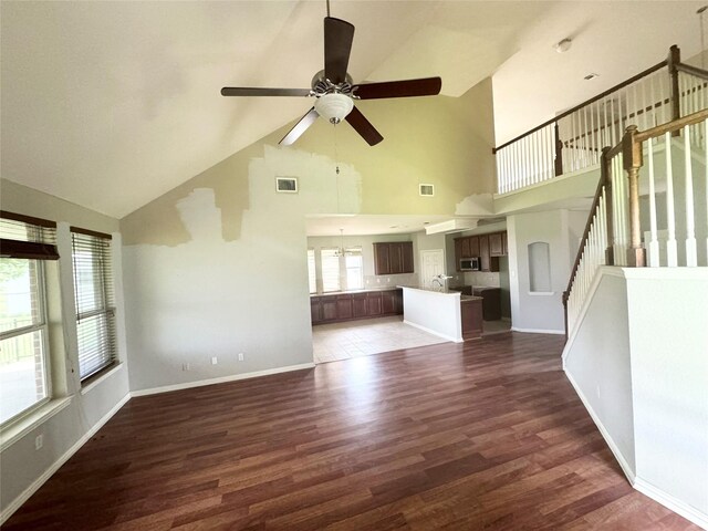 unfurnished living room with ceiling fan, dark hardwood / wood-style floors, sink, and high vaulted ceiling