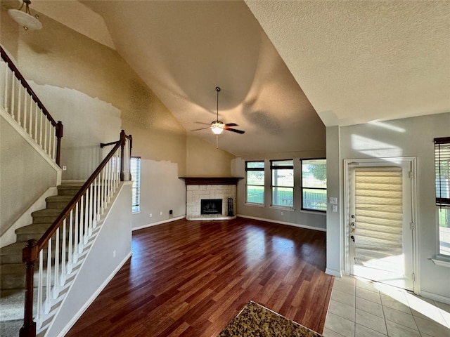 unfurnished living room featuring ceiling fan, lofted ceiling, a fireplace, and wood-type flooring