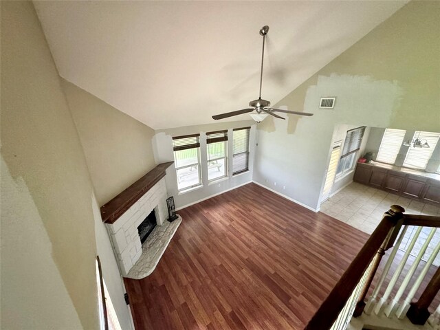 unfurnished living room with ceiling fan, high vaulted ceiling, a fireplace, and hardwood / wood-style floors