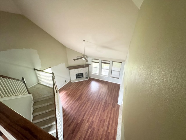 unfurnished living room with dark wood-type flooring, ceiling fan, and vaulted ceiling