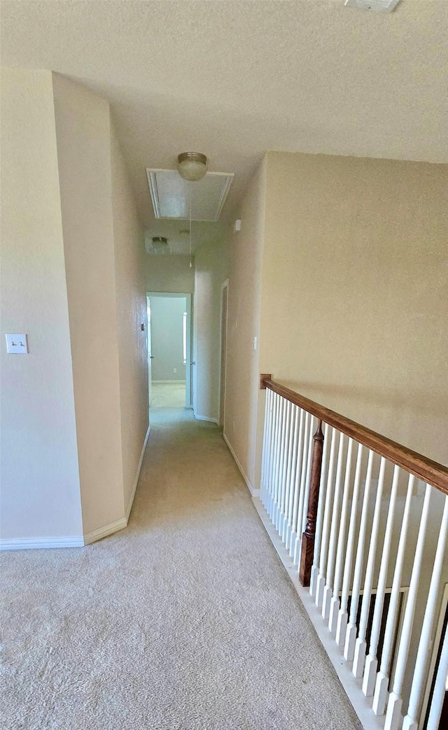 hall featuring light carpet and a textured ceiling