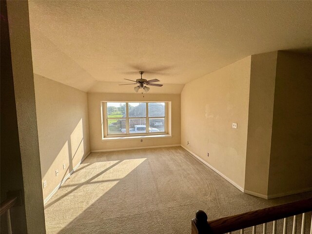 carpeted empty room featuring ceiling fan, lofted ceiling, and a textured ceiling