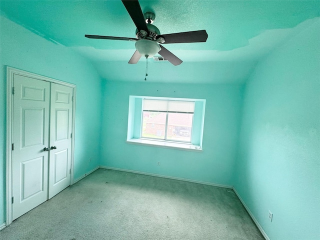 unfurnished bedroom with lofted ceiling, light colored carpet, a closet, and ceiling fan