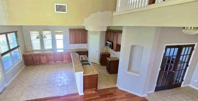 kitchen featuring light tile patterned flooring, sink, and light stone counters