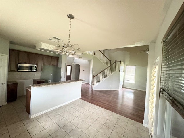 kitchen featuring light stone countertops, ceiling fan with notable chandelier, hanging light fixtures, and light tile patterned floors