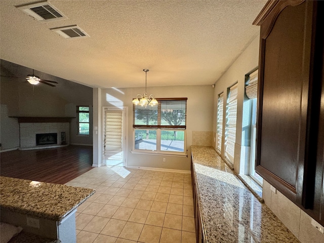 dining space featuring light tile patterned floors, ceiling fan with notable chandelier, and a textured ceiling