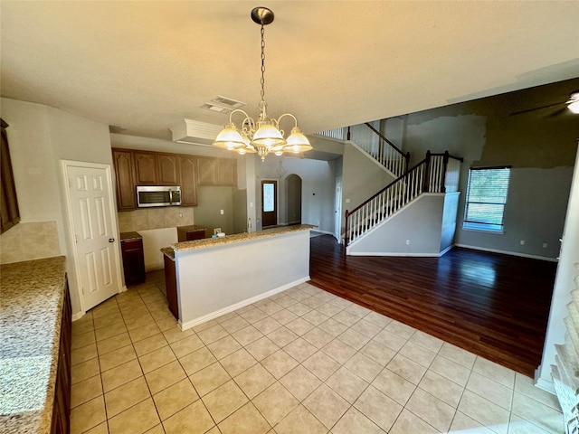 kitchen featuring pendant lighting, a chandelier, light stone counters, and light tile patterned floors