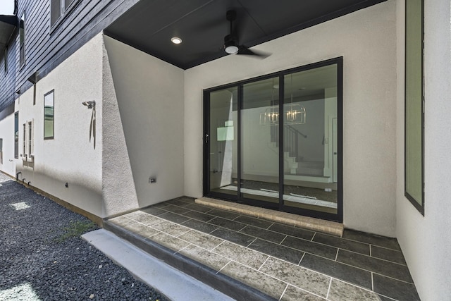 view of exterior entry featuring ceiling fan and a patio